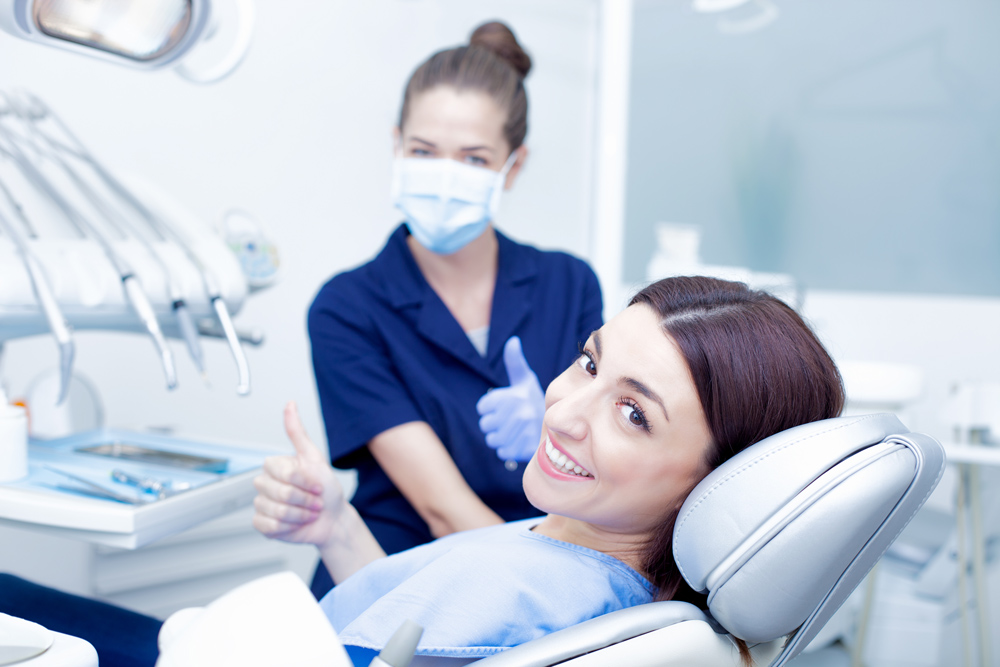 Adult Female Smiling and Looking into the Camera whilst sitting in Dentist Chair at Ennis Family Dental